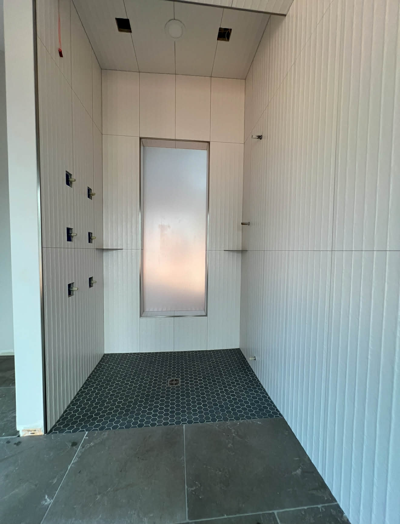 White fluted tile steam shower with dark hex floor