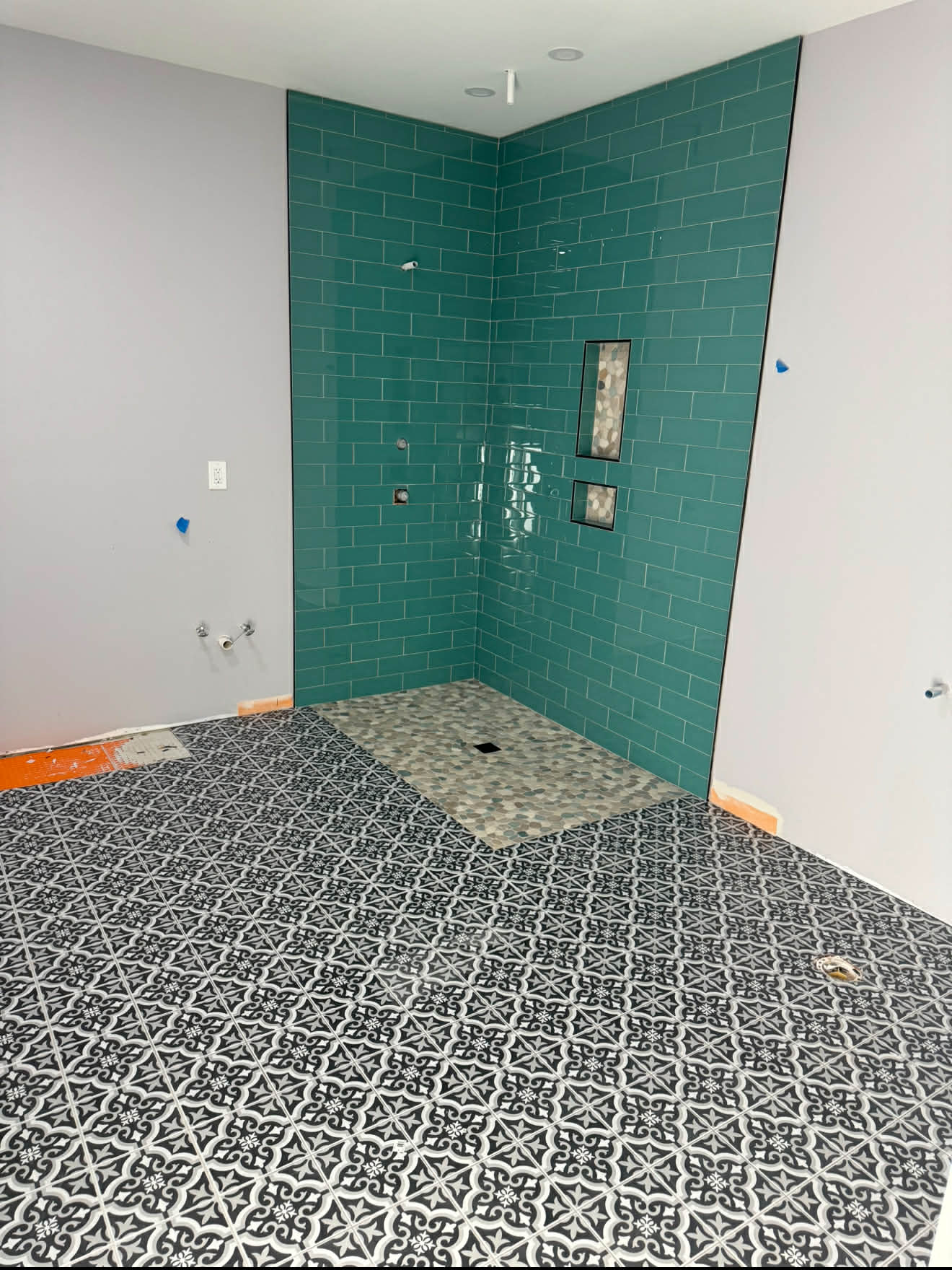 Teal subway tile shower with patterned floor