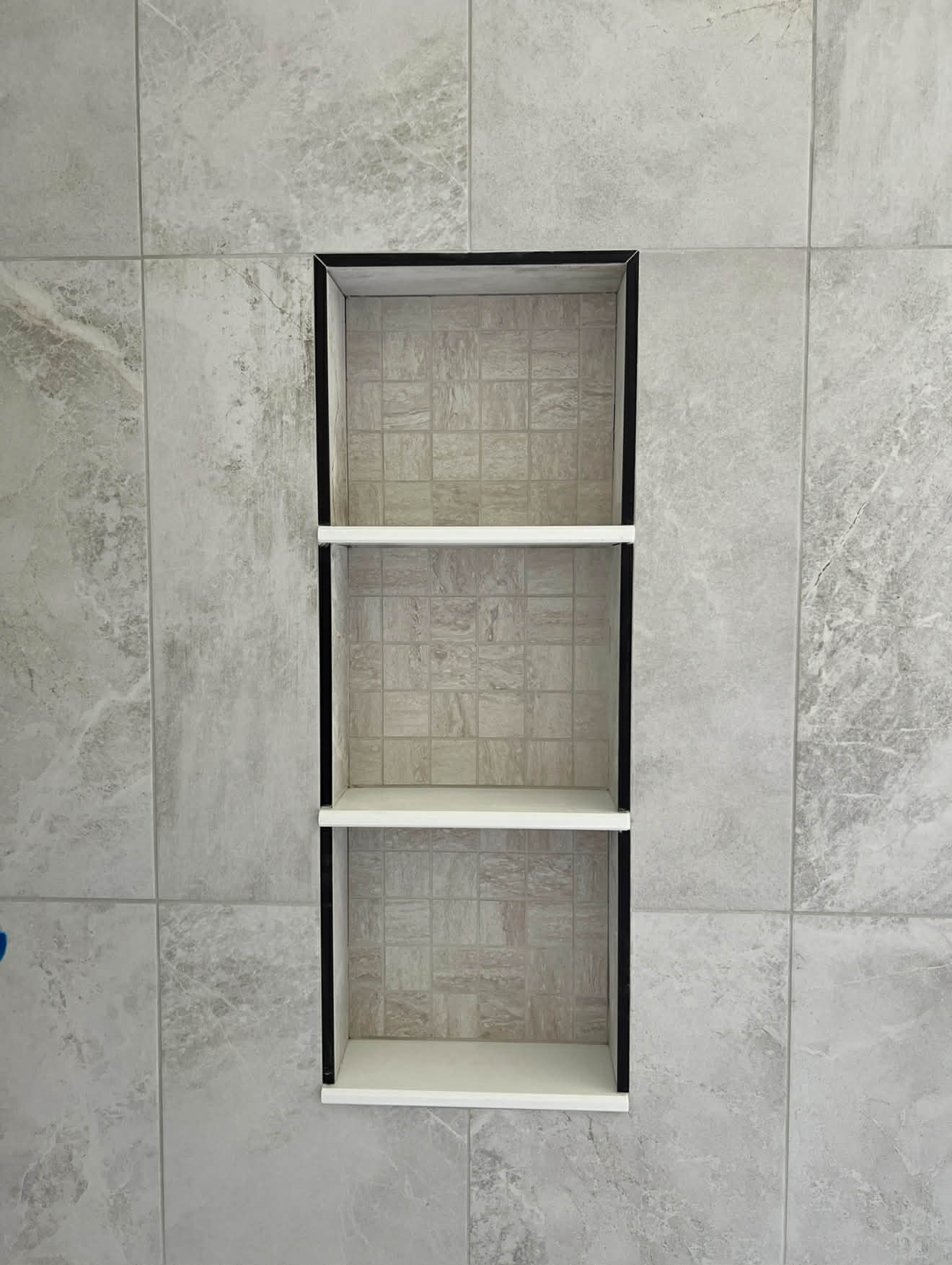 Grey stone tile shower niche with metal frame