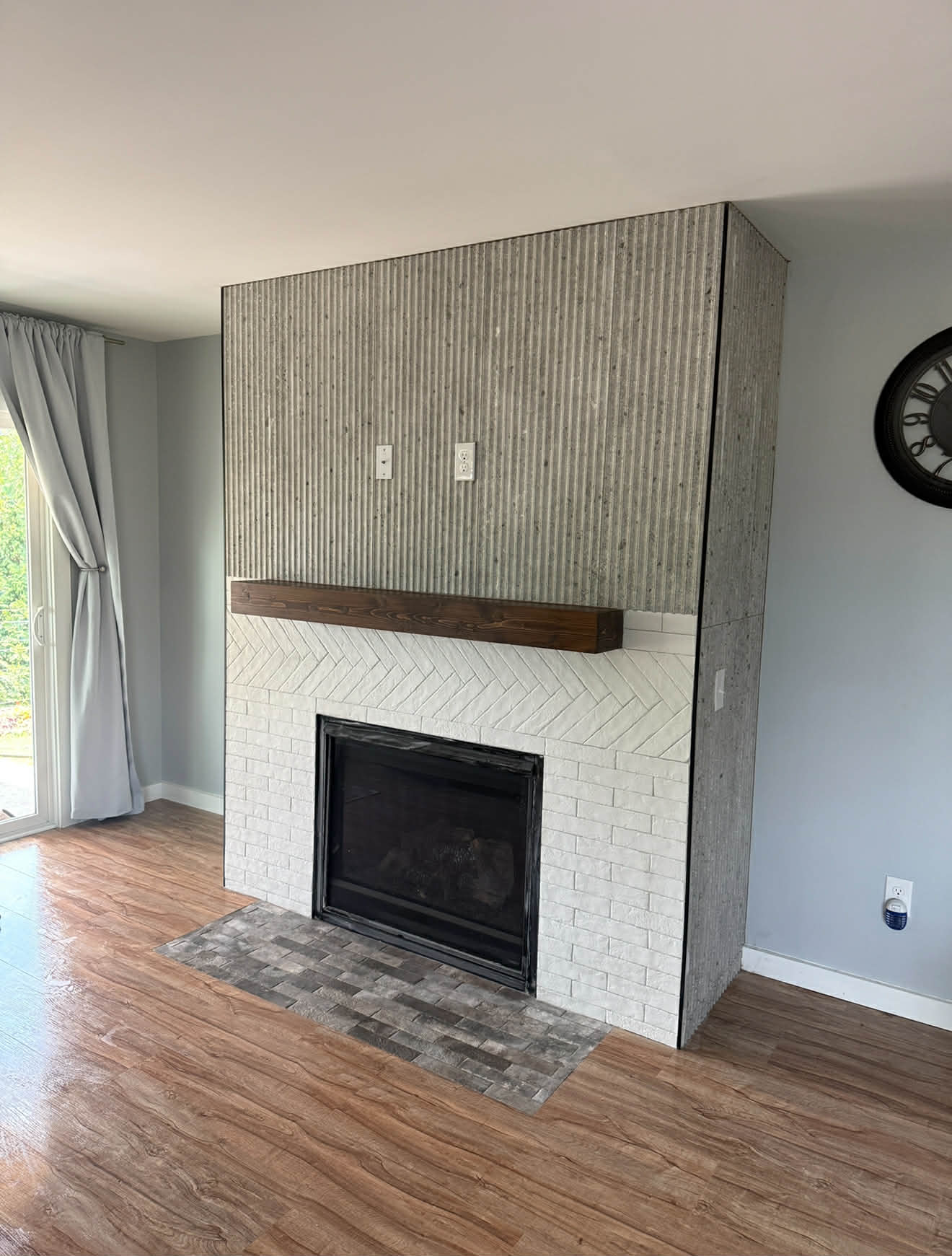 Classic fireplace with herringbone surround, fluted concrete tile and wood mantle