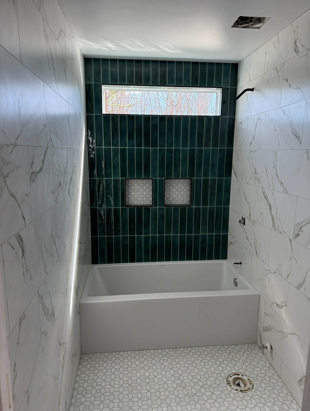 Bathtub alcove with teal vertical tile and marble surround