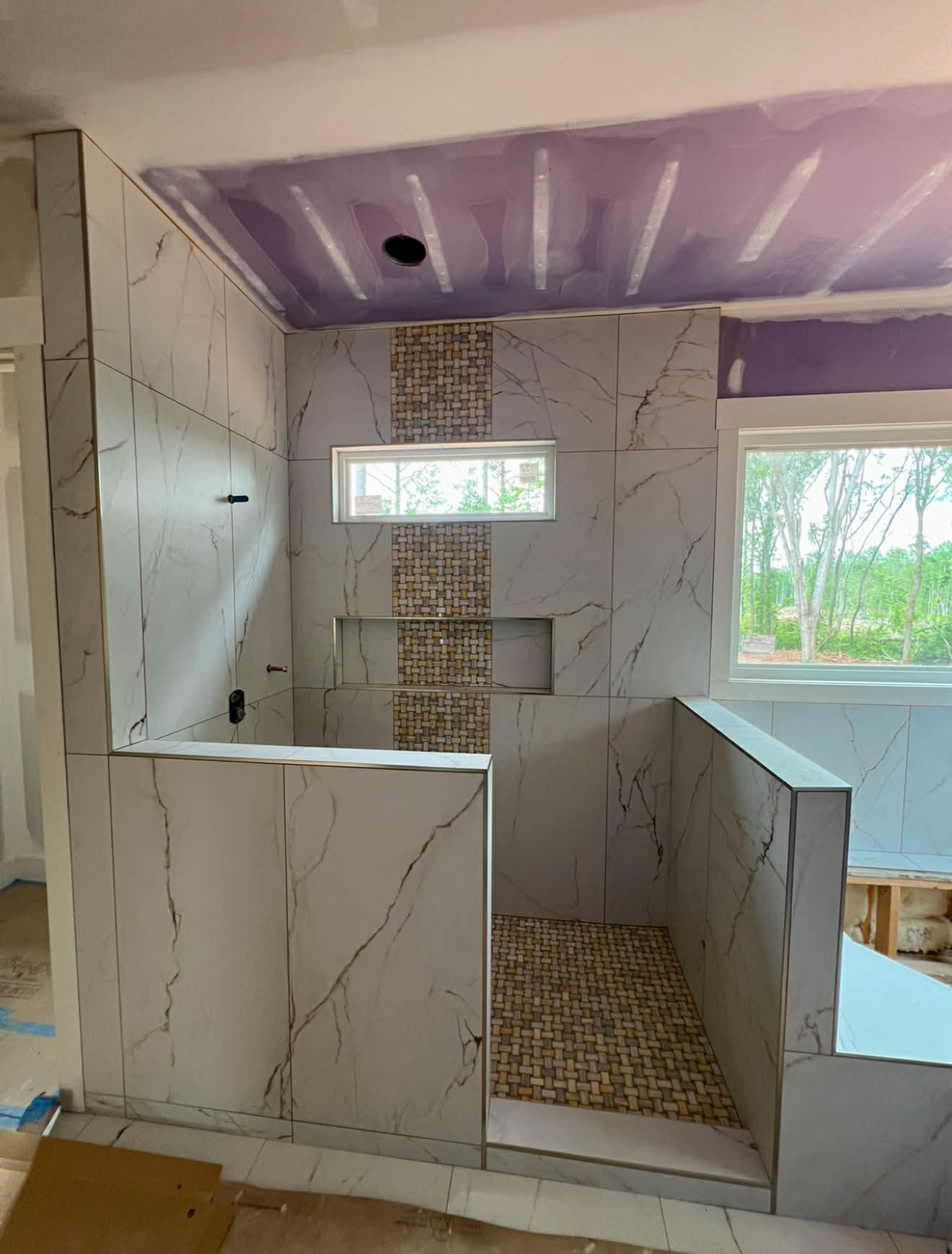 Shower under construction — dark tile with penny hex floor