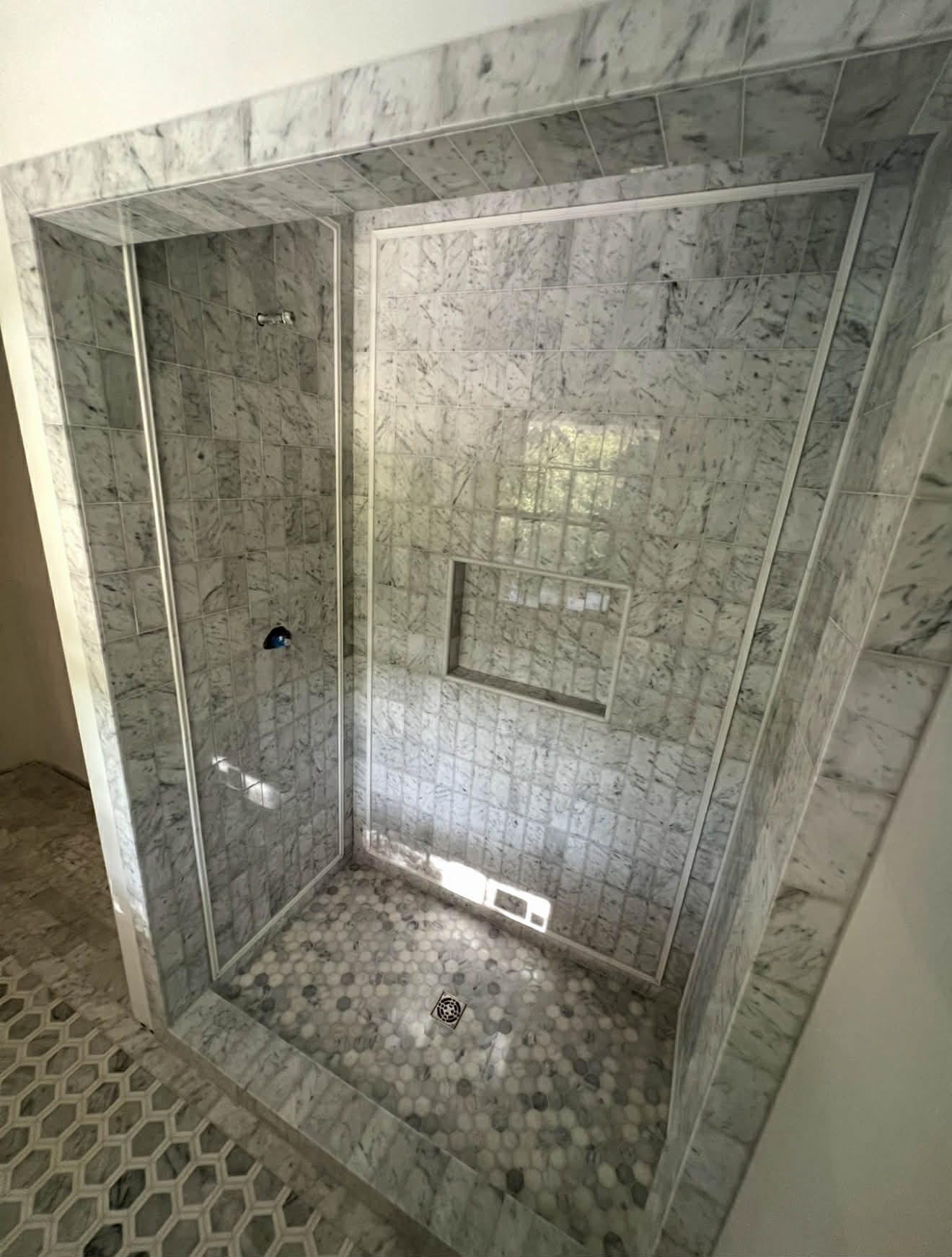 Calacatta marble shower with golden mosaic column and niche