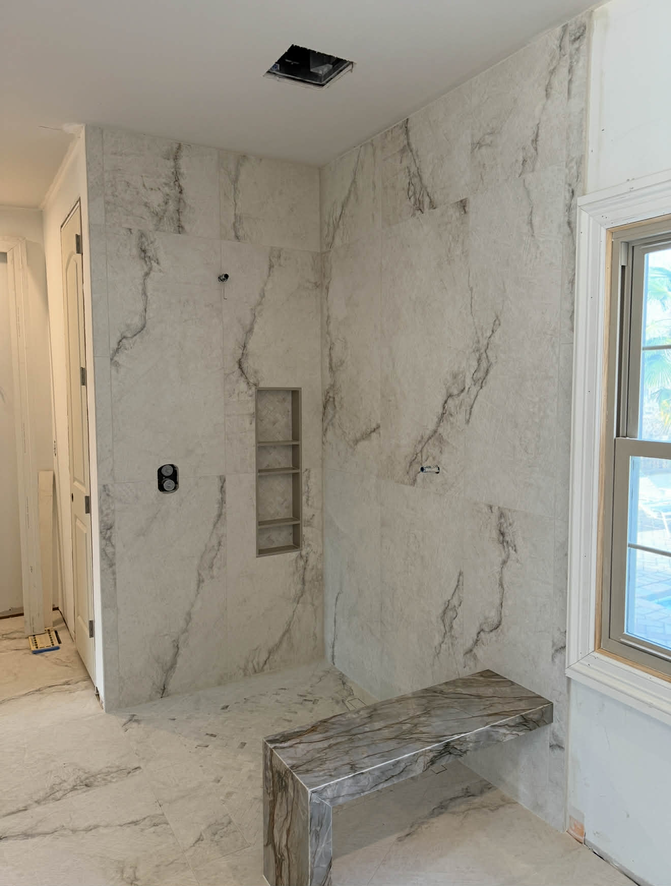 White geometric mosaic accent panel in shower