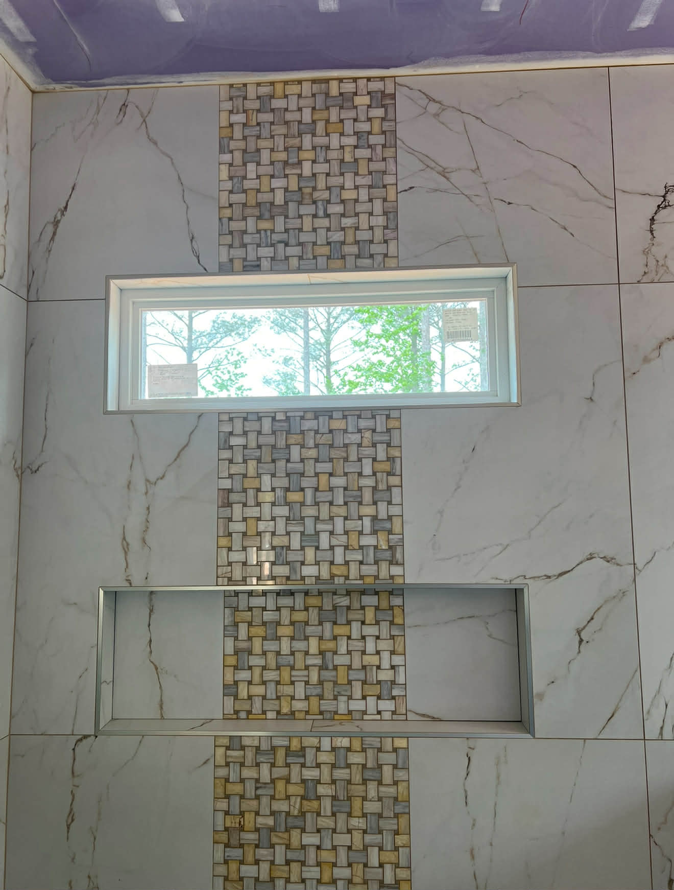 Dark and calacatta marble shower with ornate mosaic niche